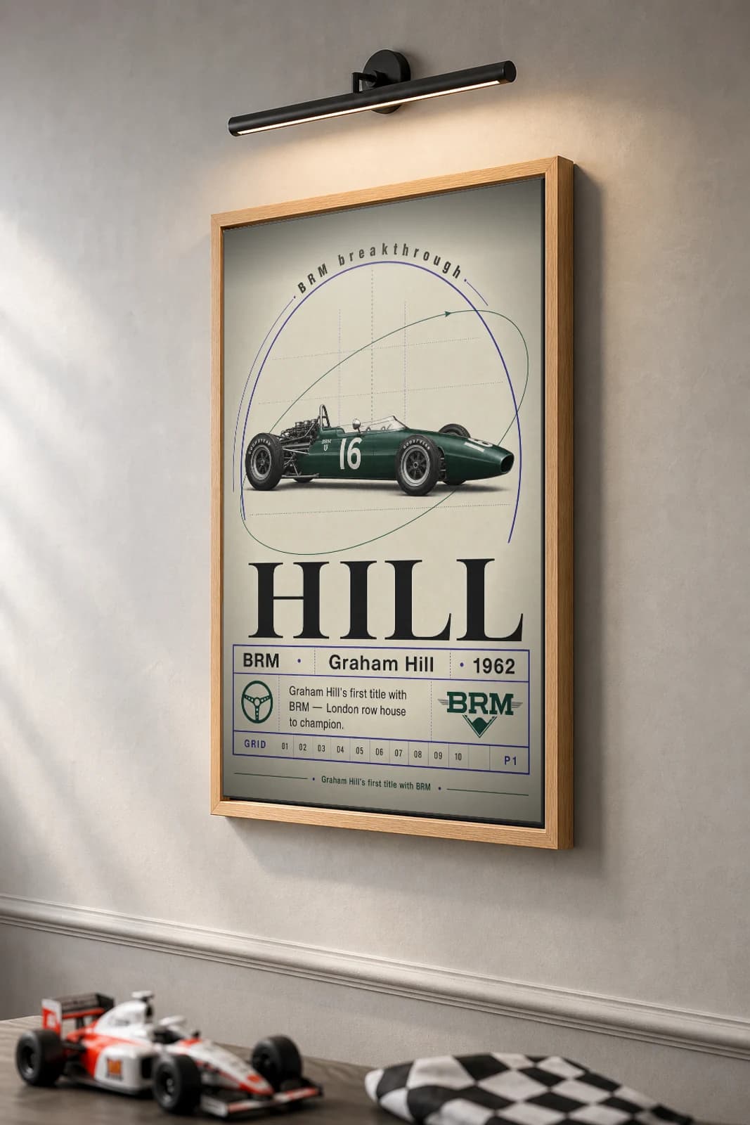 Graham Hill — Graham Hill — classic BRM 62 heritage plate Poster — 62 F1 Grid Editorial Wall Art · framed A2 — the framed print shown at a three-quarter angle on a styled gallery wall in a natural-oak frame
