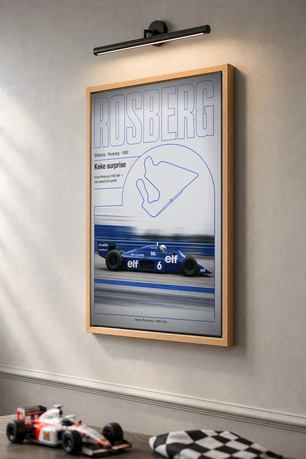 Keke Rosberg — Keke Rosberg — classic Williams Racing 82 heritage plate Poster — 82 F1 Grid Editorial Wall Art · framed A2 — the framed print shown at a three-quarter angle on a styled gallery wall in a natural-oak frame