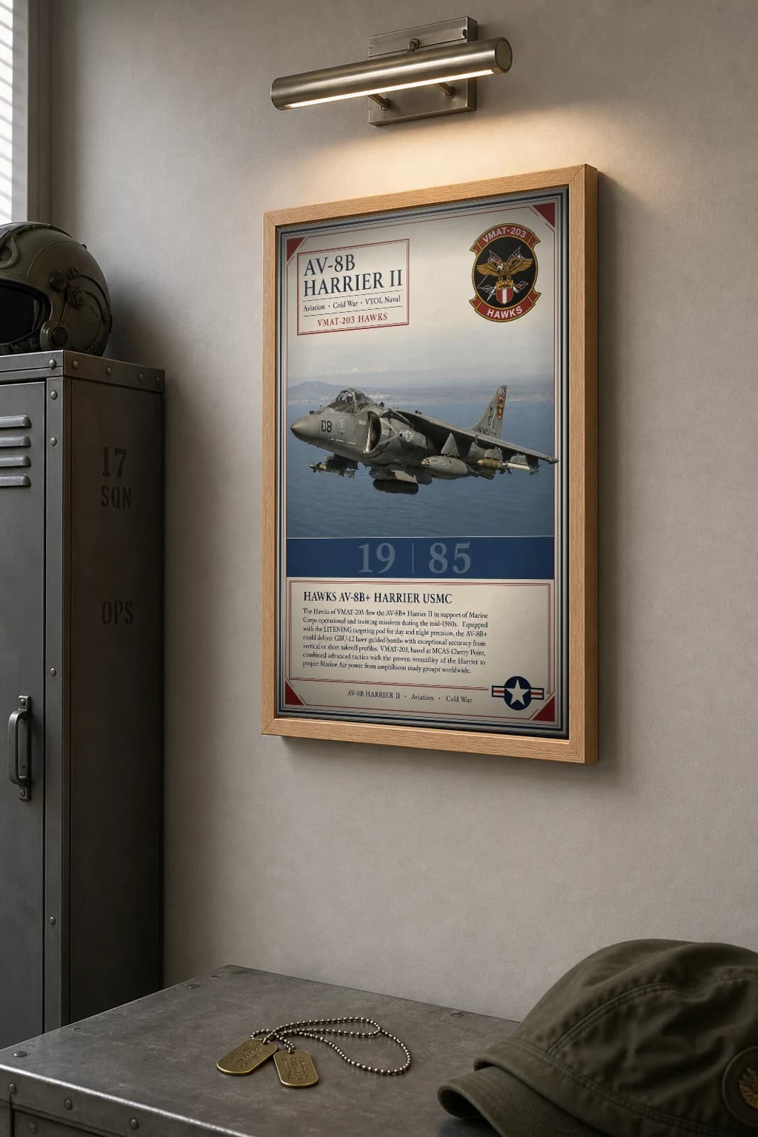 AV-8B Harrier II Poster — VMAT-203 Hawks military aviation wall art · framed A2 · 1985 — the framed print shown at a three-quarter angle on a styled gallery wall in a natural-oak frame