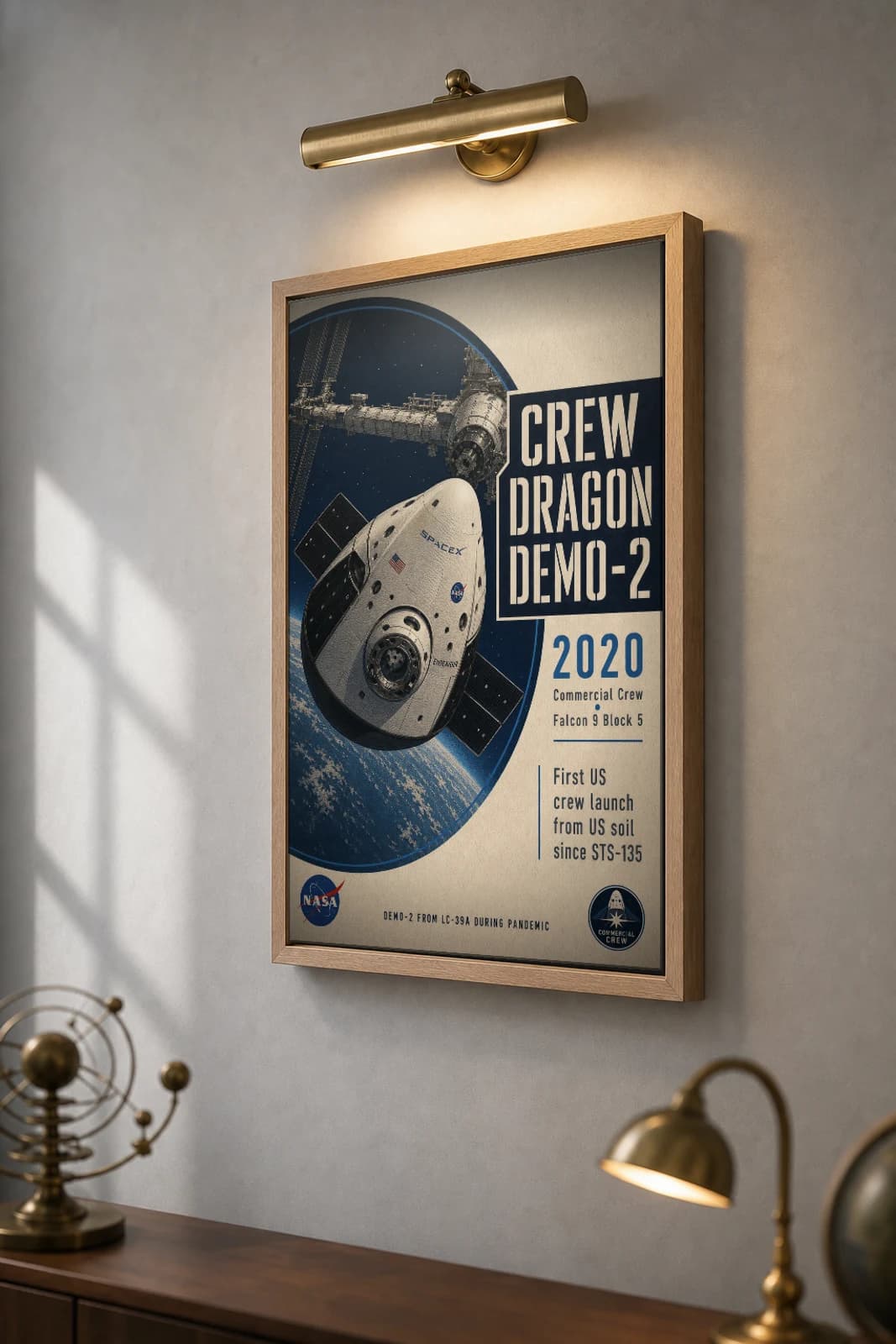 Crew Dragon Demo-2 Poster — 2020 Commercial Crew Endeavour NASA Heritage Collector Print — the framed print shown at a three-quarter angle on a styled gallery wall in a natural-oak frame