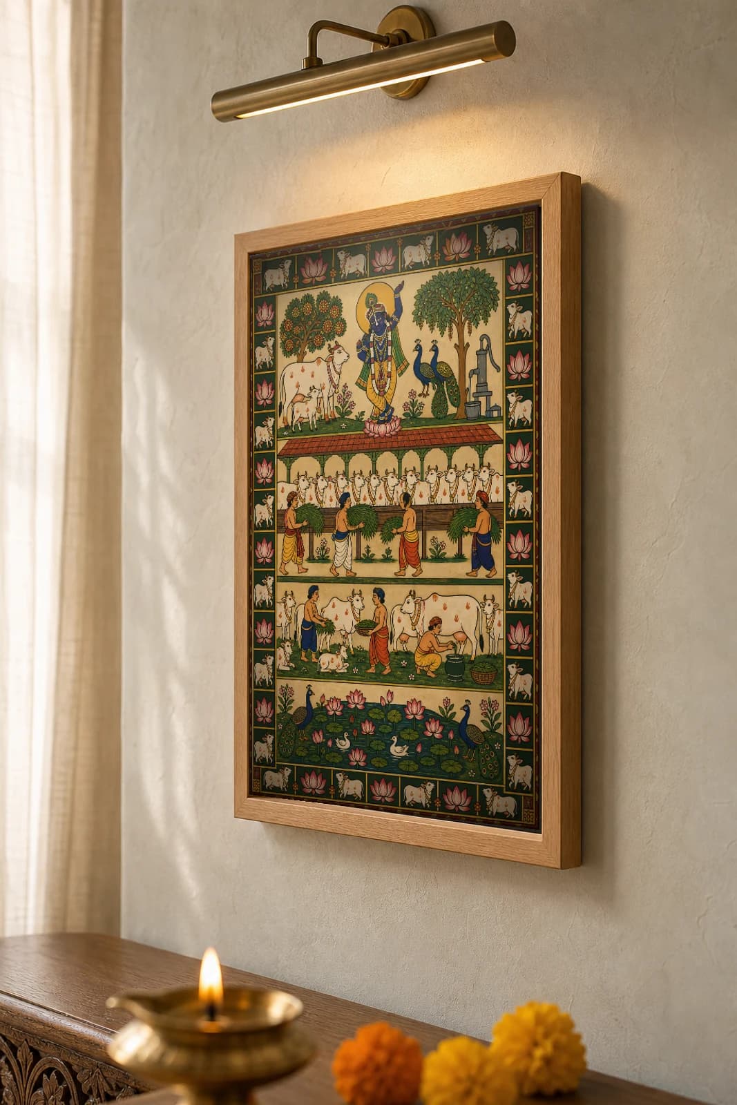 Goshala Seva Pichwai-Style Print — volunteers feeding fodder to rows of cows in a covered cow-shed below a flute Krishna, with milking, a hand-pump and a lotus pond, on warm cream cloth — the framed print shown at a three-quarter angle on a styled gallery wall in a natural-oak frame