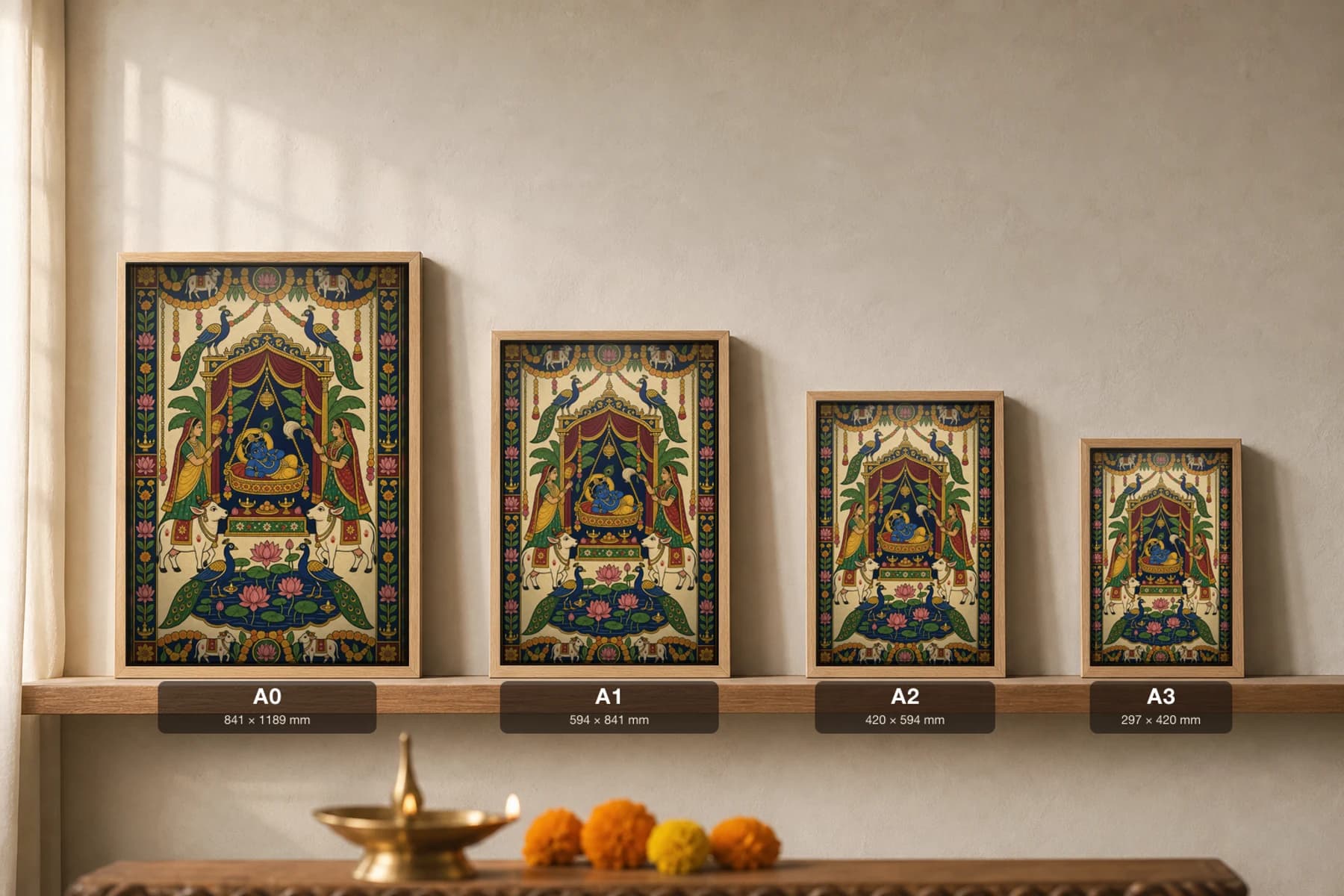 Janmashtami Jhanki Pichwai-Style Print — baby Krishna in an ornate swing-cradle under a canopy, attended by two women, with cows, peacocks and a lotus pond, on warm cream cloth — print size guide showing the artwork at A0, A1, A2 and A3 in natural-oak frames at true relative scale
