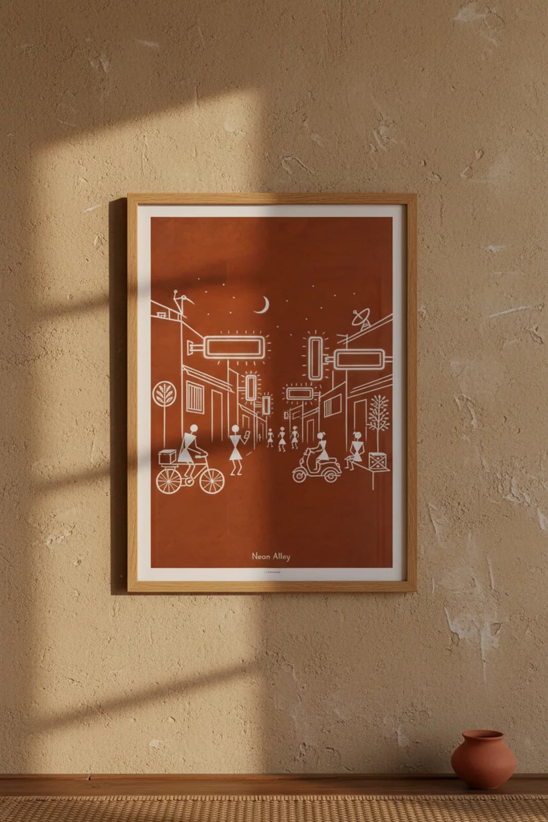 Neon Alley Warli print in natural oak A2 frame on warm-earth-neutral mud-plaster wall — rustic Indian folk art mockup