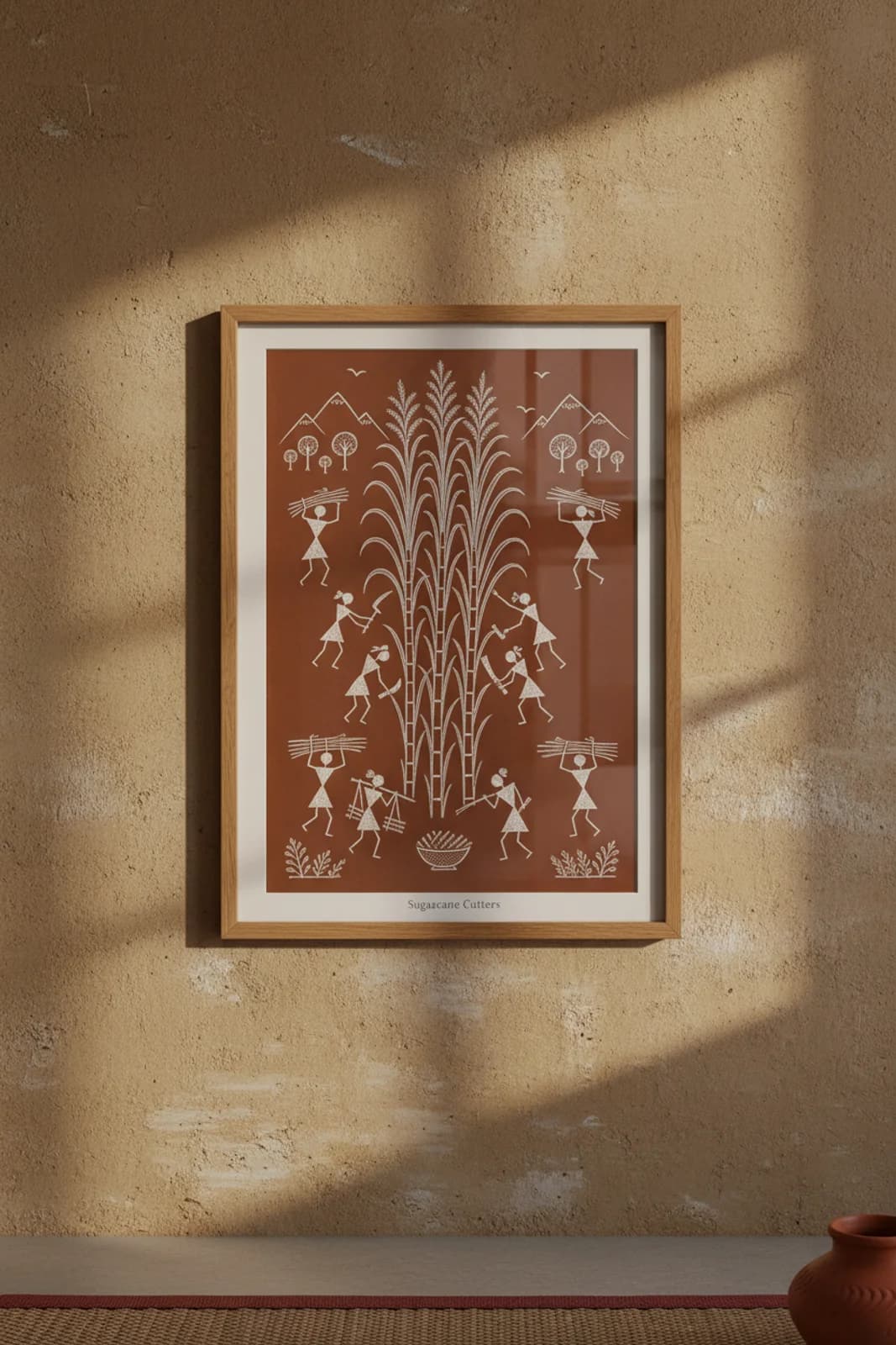 Sugarcane Cutters Warli print in natural oak A2 frame on warm-earth-neutral mud-plaster wall — rustic Indian folk art mockup