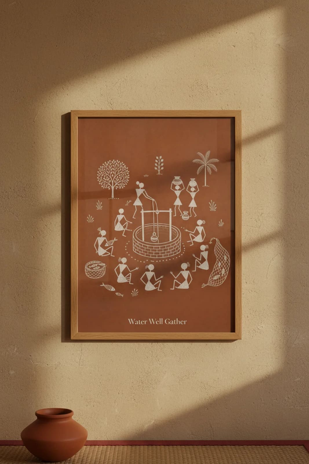 Water Well Gather Warli print in natural oak A2 frame on warm-earth-neutral mud-plaster wall — rustic Indian folk art mockup