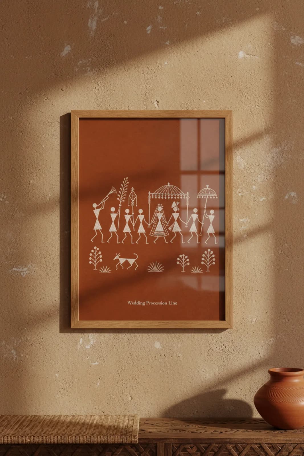Wedding Procession Line Warli print in natural oak A2 frame on warm-earth-neutral mud-plaster wall — rustic Indian folk art mockup